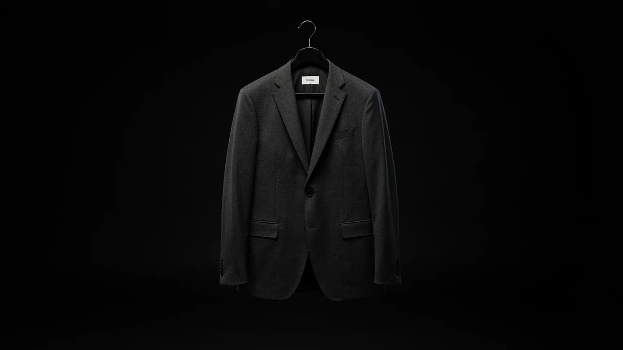 Charcoal wool blazer on a black hanger against a black backdrop